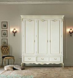 a white armoire in a room with pictures on the wall