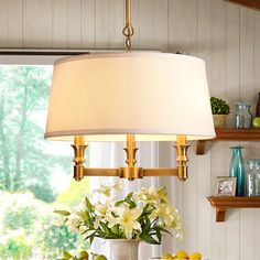 a lamp that is sitting on top of a table with fruit and flowers in front of it