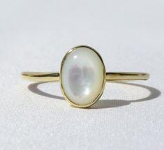 Elegant, simple and truly a classic piece. This mother of pearl ring is made from 14k solid gold or 14k solid white gold material. Set with a natural mother of pearl stone. Each pearl is unique and natural. Whether you're buying this beautiful pearl ring as a gift or for yourself, it will bring forth new beginnings and good luck. Handmade in Los Angeles, CA! Fast Shipping: It will take 1-3 business days to send out your item Packaging: Comes in an upgraded gift box, ready for gift-giving! Pearl Timeless Oval Rings With High Luster, High Luster Oval Ring In 14k Gold, Classic White Signet Ring With Round Band, High Luster 14k Gold Oval Rings, Classic White Signet Ring, Minimalist Oval Cabochon Opal Ring For Anniversary, Elegant Polished Opal Open Ring, Elegant Opal Open Ring With Polished Finish, Elegant Oval Mother Of Pearl Ring