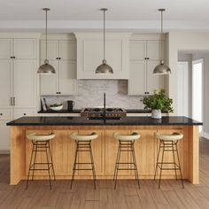 a large kitchen with white cabinets and black counter tops, along with four stools in front of the island