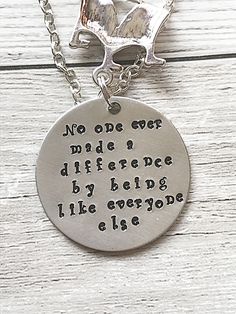 a necklace with a quote on it sitting on top of a wooden table next to a chain