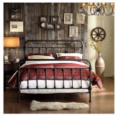 a bed with red and white sheets in a room next to a wooden panel wall