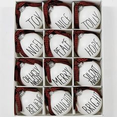 twelve white ceramic ornaments in a box with red ribbon around the edges and words written on each ornament