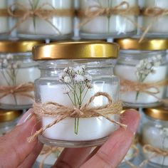 a hand holding a jar filled with white candles