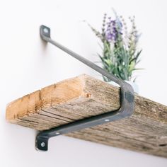 a wooden shelf with metal brackets and a potted plant on it's side