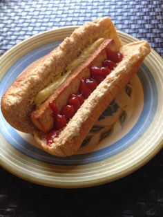 a hot dog with ketchup and mustard on a blue, yellow and white plate