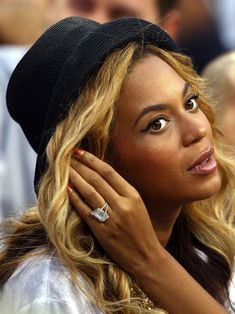 a close up of a person wearing a hat and holding her hand near her face