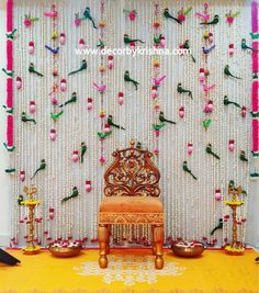 a chair sitting in front of a wall with flowers and beads hanging from it's sides