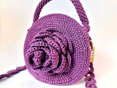 a purple crocheted purse with a gold chain hanging from it's side