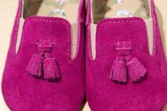 a pair of pink shoes with tassels on them