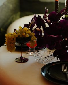 the table is set with purple flowers and candles