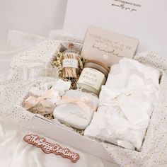 an open gift box filled with personal care items on top of a white bed sheet