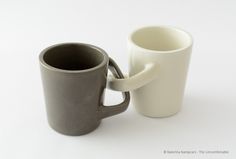 two coffee mugs sitting next to each other on a white surface with no background