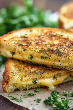 two grilled cheese sandwiches stacked on top of each other with parsley sprigs