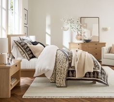 a bedroom with white walls and wooden flooring has a bed, dresser, chair, and window in it