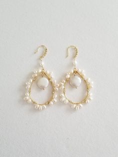 the earrings are made with white pearls and gold plated wire, on a white background