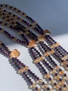 Double Strand Waist Bead, a stunning blend of purple crystal glass beads with elegant gold and brown accents. Why You'll Love It: Exquisite Sparkle: Beautiful purple crystal glass beads create a radiant, eye-catching shimmer. Elegant Accents: Gold and brown crystal glass beads add a touch of luxury and sophistication. Perfect Fit: The adjustable double strand design ensures comfort and a secure fit for all body types. Cultural Beauty: This piece reflects the rich heritage of Ivorian craftsmanshi Gold Beaded Necklaces With Heart Beads For Party, Gold Beaded Necklace With Heart Beads For Parties, Purple Glass Beaded Necklaces With Round Beads, Gold Beaded Glass Crystal Necklaces, Purple Glass Beaded Necklace With Round Beads, Elegant Gold Polished Waist Beads, Bohemian Multi-strand Waist Beads With Spacer Beads, Adjustable Multicolor Gold Waist Beads, Gold Amethyst Beaded Necklace With Faceted Beads