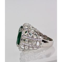 This is part of Chairish’s Fine Jewelry assortment.  Oval Emerald 12.25 Carat Diamond Surround 8.85 Carat Total Weight 21.10 Carat  This oval Emerald weights in at 12.25 carats and is a gorgeous Emerald Green with transparency. The Diamonds weigh in at 8.85 Carats and the mount is exceptional the Diamonds are VS1-VS2 and G-J in color. This is a bombe mount. The shoulders of the ring are embellished with baguette cut Diamonds in the center border with a perimeter of round cut Diamonds accents. Th Luxury Green Marquise Diamond Ring, Luxury Diamond Cluster Ring With Gemstones, Luxury Cubic Zirconia Diamond Ring For Evening, Luxury Marquise Emerald Ring, Luxury Emerald Birthstone Ring, Luxury Green Diamond Ring, Luxury Marquise Emerald Ring With Diamonds, Gia Certified Dazzling Diamond Ring For Formal Occasions, Dazzling Gia Certified Diamond Ring For Formal Occasions