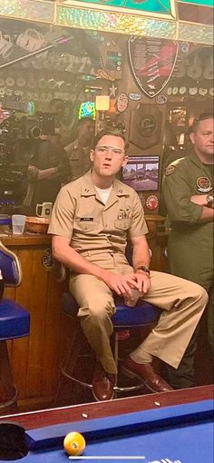 two men in uniform sitting at a pool table