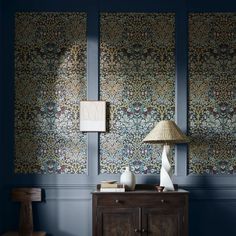 a room with blue walls and two lamps on top of the sideboard in front of it