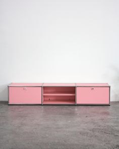 a pink cabinet sitting on top of a cement floor