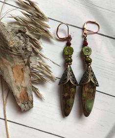 Beautiful mottled Olive green stones cloaked in a brass filigree Cone dangle underneath  a Czech glass flower and Garnet rondelle. This one of a kind pair measures 2-1/2 inches long. Brass and copper findings with Copper ear wires. Bohemian Jade Earrings, Bohemian Green Copper Jewelry, Nickel Free Bohemian Jade Earrings, Bohemian Nickel Free Jade Earrings, Green Bohemian Copper Wire Earrings, Bohemian Green Earrings With Copper Wire, Artisan Green Copper Jewelry, Green Bohemian Earrings With Copper Wire, Bohemian Bronze Jewelry With Copper Wire