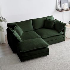 a large green couch sitting on top of a white rug in a living room next to a window