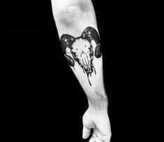 a man's arm with a black and white tattoo design on the left forearm