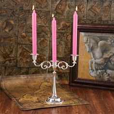 two pink candles sitting on top of a silver candelabra with ornate designs