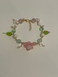 Green,pink, and clear fairy core bracelet. Whimsical Flower Jewelry For Party, Whimsical Flower-shaped Jewelry, Bracelet Ideas Coquette, Whimsical Adjustable Jewelry With Flower Charm, Spring Rose Gold Flower Bracelets, Spring Rose Gold Flower Bracelet, Fairy Core Bracelets, Cute Pink Bangle Charm Bracelet, Dainty Pink Beaded Bracelets For Party