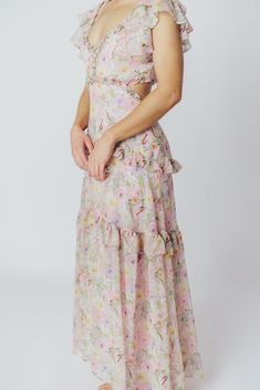 We think the gorgeous Millie Maxi Dress from ASTR is fit for a princess. It's all flowers and ruffles and utterly romantic, perfect for a special vacation dinner, or for when you want to RSVP "elegant" to a spring wedding or shower. This dress doesn't skimp on the feminine details, and deserves a place of honor in your closet! FIT: Runs true to size. Bust is fitted, with a low neckline and bodice cut-outs. MATERIAL: GARMENT DETAILS: Floral chiffon maxi dress, with a plunging V-neckline, multi-tiered ruffled sleeves, and side cut-outs under the bust. Features a full, flowy skirt with ruffle accents, a smocked back panel, and a back self-tie detail at the shoulders. SIZE GUIDE: XS (00-0) / S (2-4) / M (6-8) / L (10-12) MODEL DETAILS: ﻿Heather is wearing size S. Mackenzie - Size S Heather - S Flirty Floral Print Midi Dress For Garden Party, Feminine Ruffle Hem Dress For Garden Party, Flirty Midi Dress With Floral Print For Garden Party, Feminine Ruffled Dress For Garden Party, Flirty Ruffled Midi Dress For Garden Party, Spring Garden Party Flowy Ruffle Dress, Feminine Floral Print Ruffle Dress With Ruffled Straps, Feminine Floral Dress With Ruffles For Vacation, Maxi Length Ruffled Skirt Dress For Garden Party