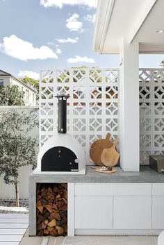 an outdoor pizza oven is built into the side of a white fenced in area