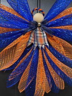 an orange and blue mesh wreath hanging on a door