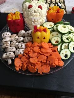 a platter filled with vegetables and halloween themed treats on top of a black table