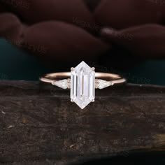 an emerald and diamond ring on top of a piece of wood with a brown background