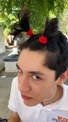 a man with black hair and red bows on top of his head looking at the camera