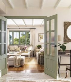 an open door leading to a living room with white furniture and green trim on the walls