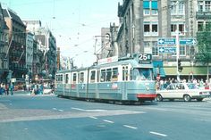 a trolley car traveling down a street next to tall buildings and people walking on the sidewalk