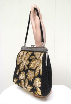 "* Exquisite, fancy woven and beaded purse c 1960s * Bright metallic gold woven on white background in floral design * Tiny black seed beads background, sides and handle * Intricate botanical silvertone metal filigree frame * Single beaded cord strap * Black satin lining with two side pockets * Kiss clasp closure No label Excellent condition - like new. Height: 7\" Width: 7\" Depth: 3\" Handle length: 13\" (total) Please view my Shop Policies prior to placing an order as all sales are final: htt Beads Background, Filigree Frame, Fabric Handbags, Floral Purse, Faux Leather Handbag, Beaded Evening Bags, Fancy Beads, Printed Handbags, Top Handle Handbags