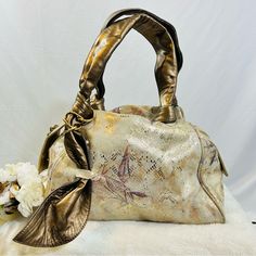 a gold purse sitting on top of a white blanket next to a bouquet of flowers