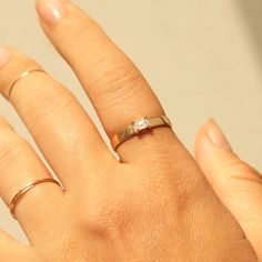 a woman's hand with two gold rings on top of her finger and the other ring