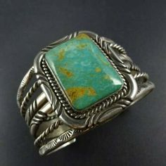 "VINTAGE NAVAJO BRACELET DESCRIPTION: This impressive cuff features a rectangular specimen of Ajax Mine turquoise, light blue-green with golden brown matrix. The gemstone is secure in smooth bezel, on a foundation of heavy gauge vintage sterling silver. Thick twisted silver rope alternates between the chisel stamped and hand-stamped features of the cuff. This bracelet will be a cherished addition to your collection of fine vintage Native American jewelry. MEASUREMENTS: Interior of the cuff measu Antique Turquoise Bangle Cuff Bracelet, Elegant Turquoise Bracelet With Patina, Elegant Turquoise Bracelets With Patina, Formal Turquoise Rectangular Jewelry, Vintage Green Bracelet With Patina, Luxury Green Rectangular Bracelets, Vintage Blue Rectangular Jewelry, Unique Green Rectangular Jewelry, Classic Turquoise Cuff Bracelet Gift