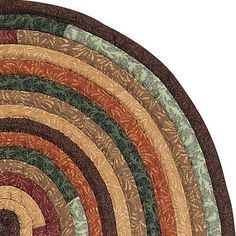 an oval rug with multicolored circles on the center is shown in brown, green, and tan