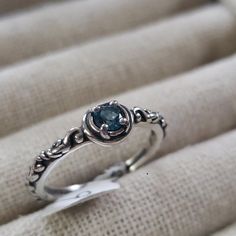 a silver ring with a blue stone in it's center on a white cloth