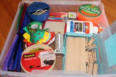 a plastic container filled with craft supplies on top of a wooden table