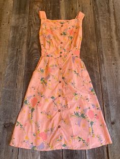 a pink dress with flowers on it sitting on a wooden floor