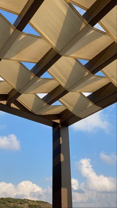 the underside of a large outdoor structure under a blue sky with clouds in the background