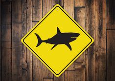 a yellow shark crossing sign sitting on top of a wooden floor next to a wall