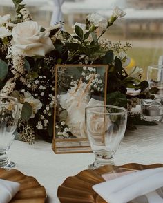 the table is set with white flowers and place settings