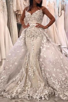 a woman standing in front of dresses on display at a bridal fashion show,